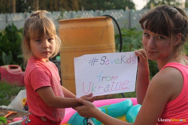 Girls holding a sign with "#SaveKids from Ukraine"